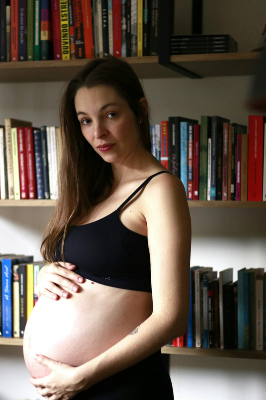 Pregnant woman posing in front of a bookcase.